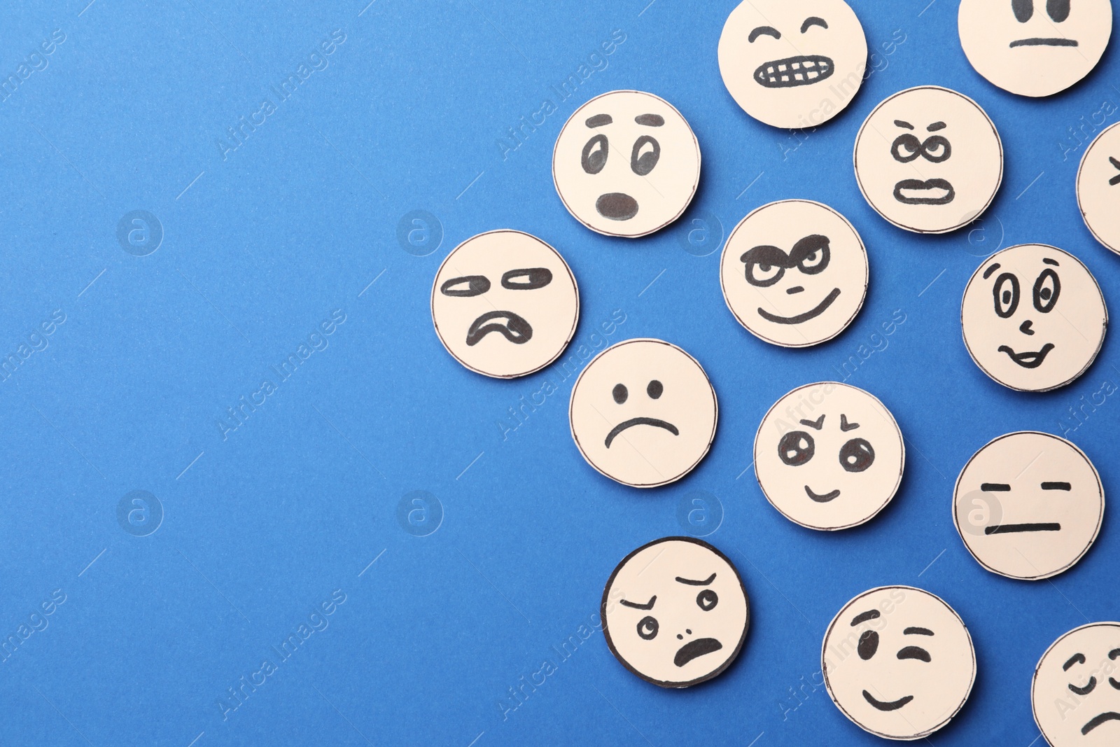 Photo of Many faces with different emotions on blue background, flat lay. Space for text