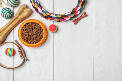 Photo of Bowl with food for dog or cat and accessories on wooden background. Pet care