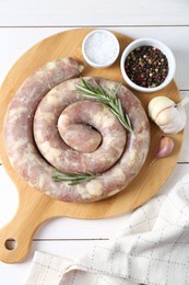 Photo of Raw homemade sausage, garlic and spices on white wooden table, flat lay