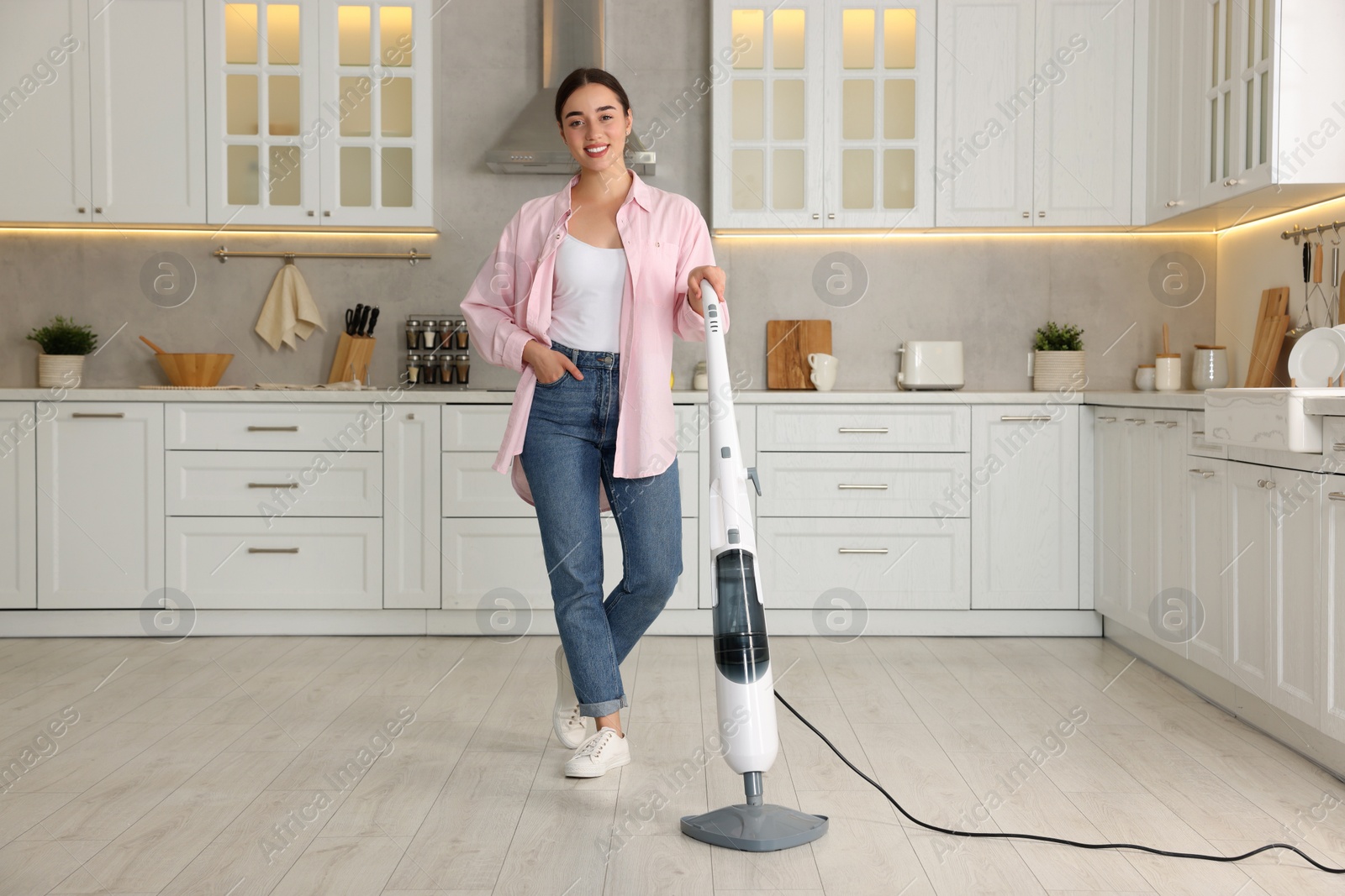 Photo of Happy woman with steam mop in kitchen at home