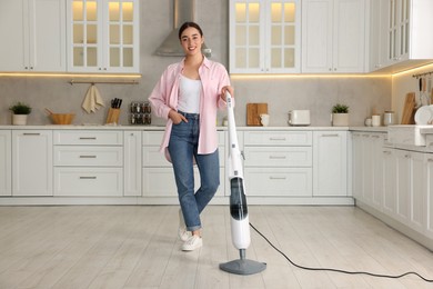Happy woman with steam mop in kitchen at home