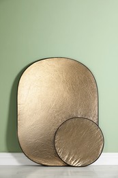 Photo of Studio reflectors near pale green wall in room. Professional photographer's equipment