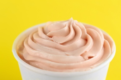 Cup with tasty frozen yogurt on yellow background, closeup