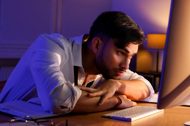 Photo of Tired young man working late in office