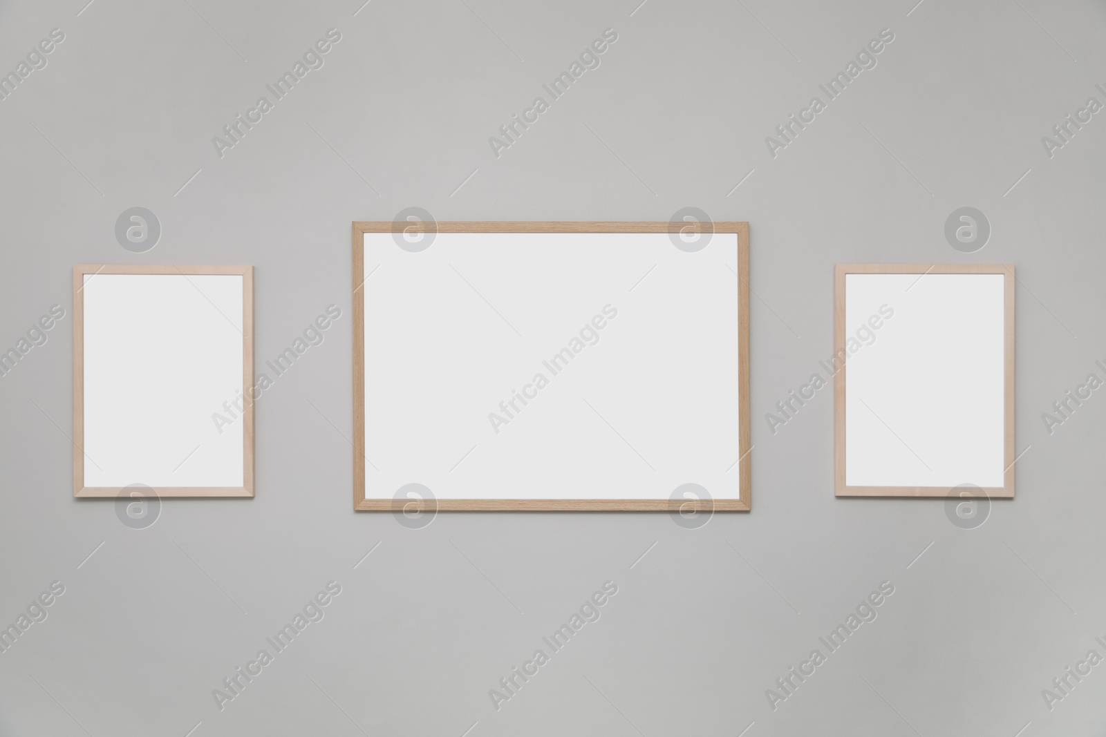 Photo of Empty frames on grey wall. Mockup for design