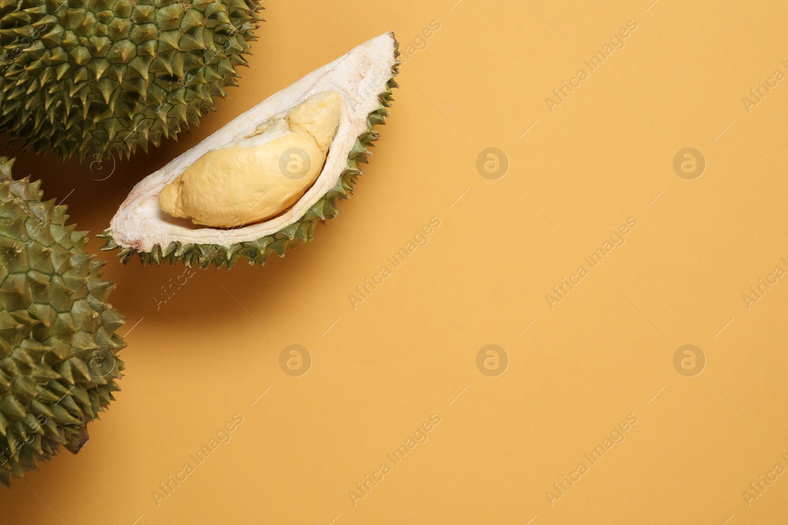 Photo of Fresh ripe durians on orange background, flat lay. Space for text