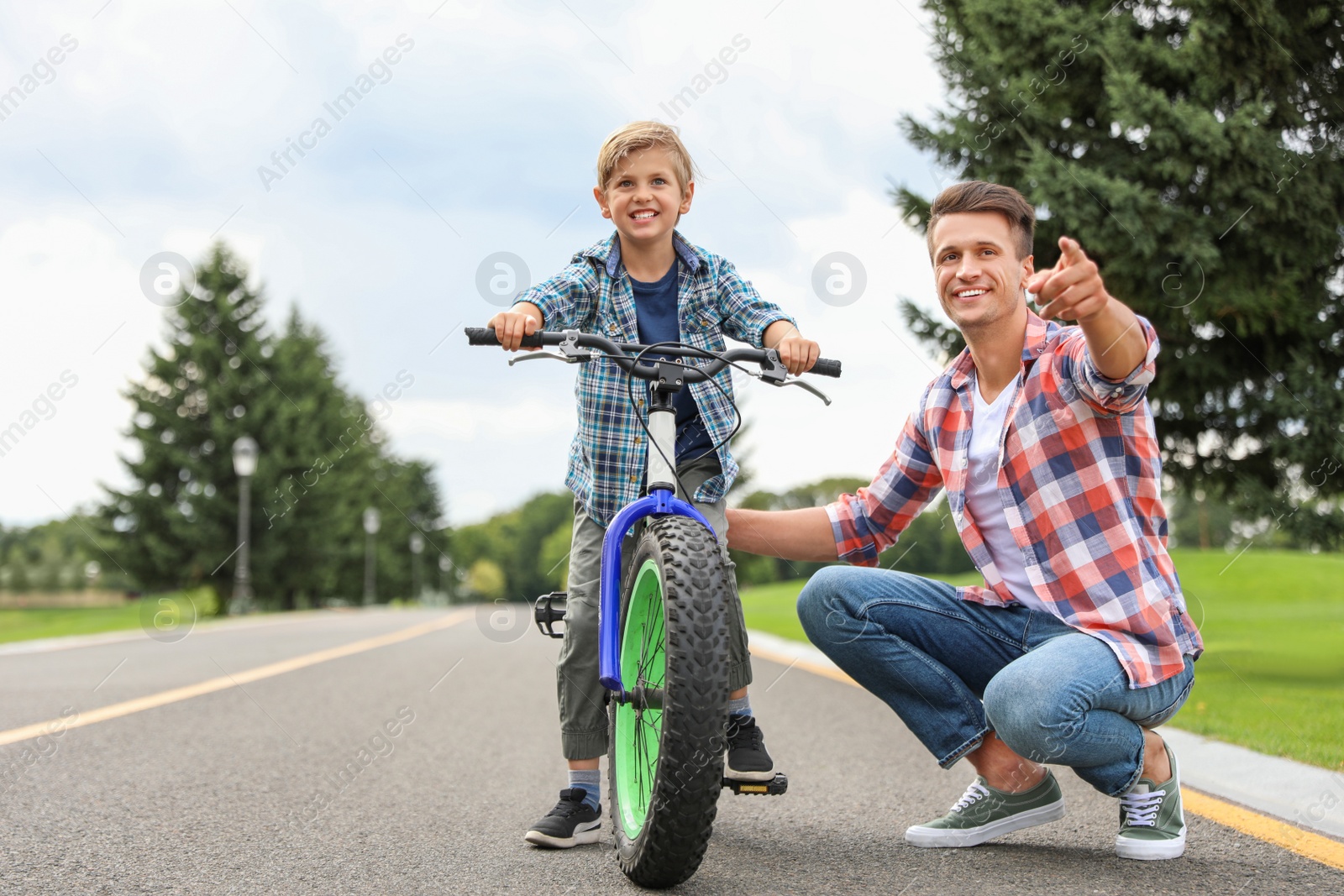 Photo of Dad teaching son to ride bicycle outdoors