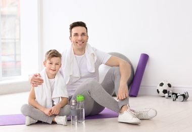 Photo of Dad and his son with bottles of water in gym