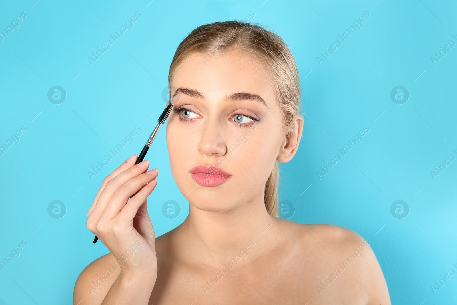 Photo of Portrait of young woman with beautiful natural eyelashes holding brush on color background