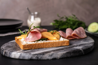 Photo of Delicious sandwich with ham on black table