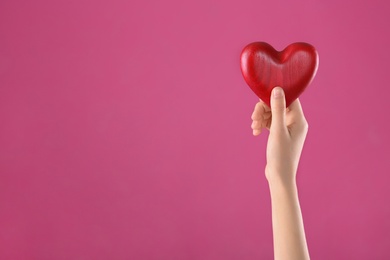 Photo of Woman holding decorative heart in hand on color background, space for text