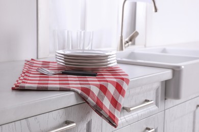 Photo of Dry towel and clean dishware on white countertop near sink in kitchen