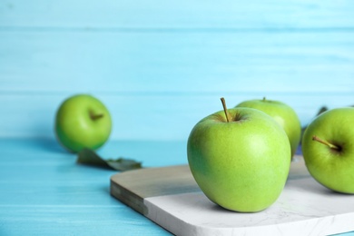 Ripe green apples on light blue wooden table. Space for text