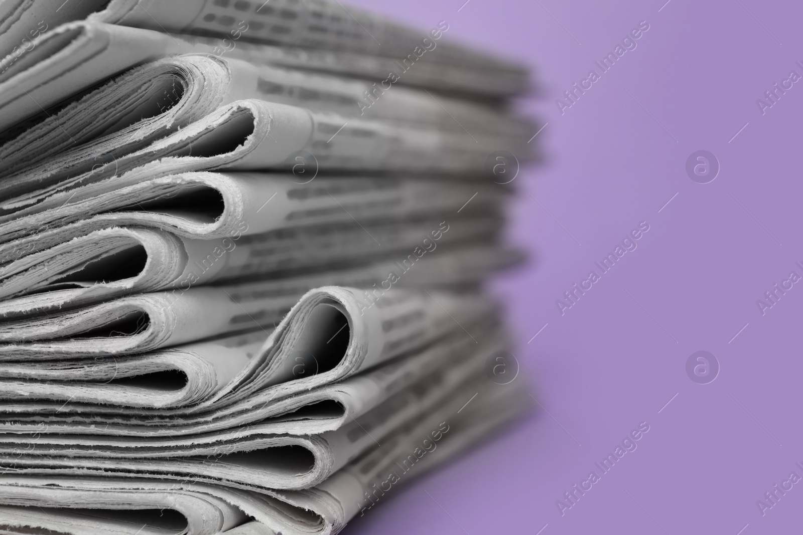 Photo of Stack of newspapers on light violet background, closeup. Journalist's work