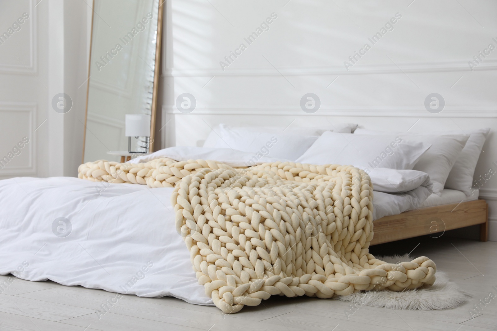 Photo of Soft chunky knit blanket on bed in stylish room interior