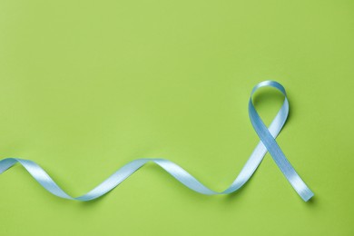 Light blue awareness ribbon on green background, top view. Space for text