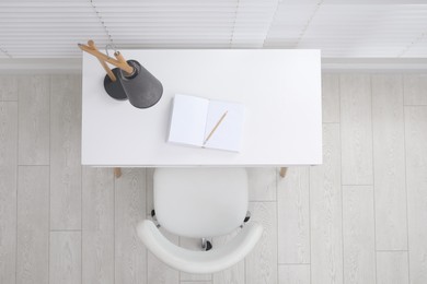 Photo of Stylish workplace with white desk and comfortable chair near window indoors, top view. Interior design