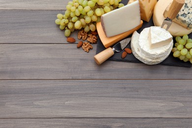 Different types of delicious cheeses and snacks on wooden table, top view. Space for text
