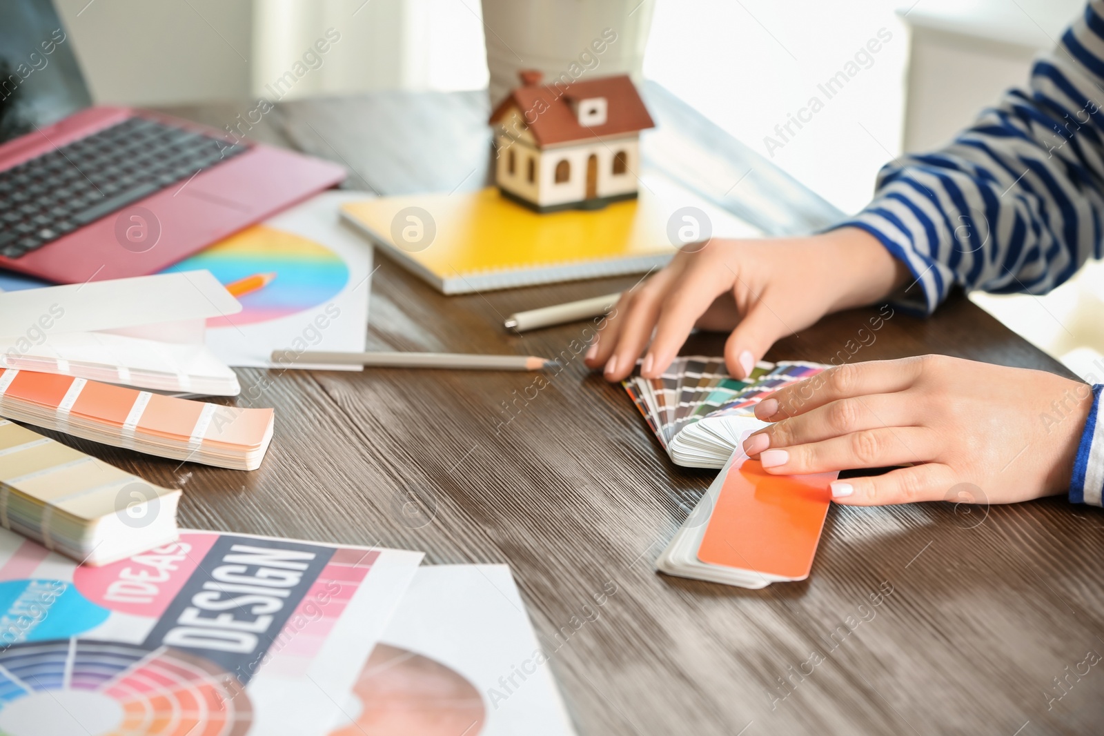 Photo of Female designer working with color palette samples at table