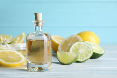 Photo of Citrus essential oil on white wooden table. Space for text