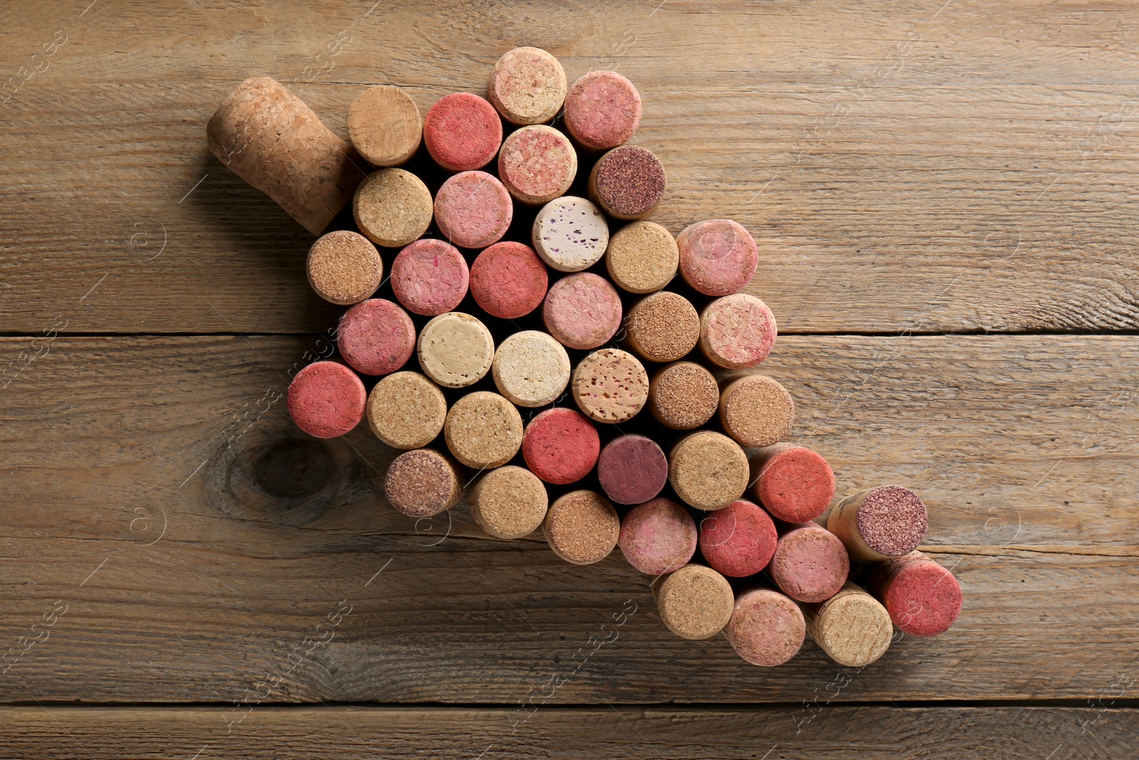 Photo of Grape made of wine bottle corks on wooden table, top view