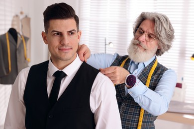 Photo of Professional tailor working with client in atelier