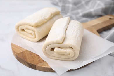 Raw puff pastry dough on white marble table, closeup