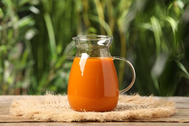 Tasty carrot juice on wooden table outdoors