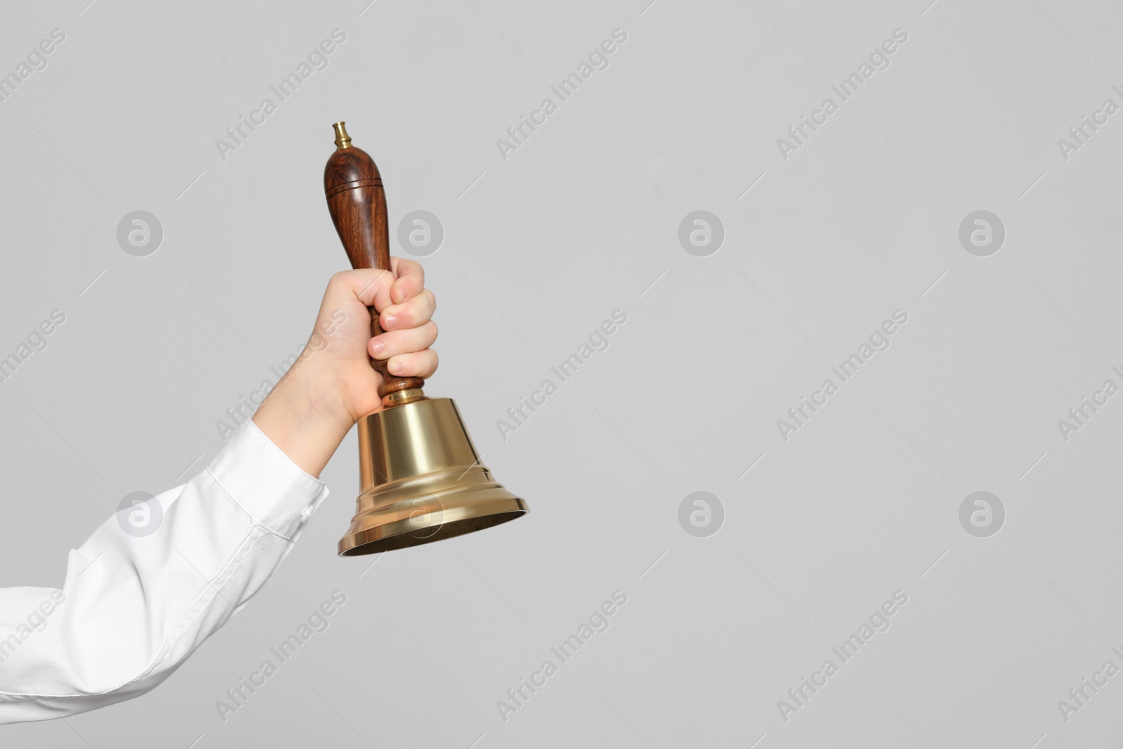 Photo of Pupil with school bell on light grey background, closeup. Space for text