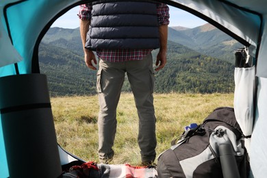 Photo of Man in mountains on sunny day, view from camping tent