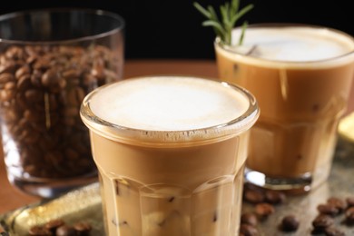 Refreshing iced coffee with milk in glasses on table, closeup