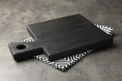 Photo of Black cutting board and napkin on grey table