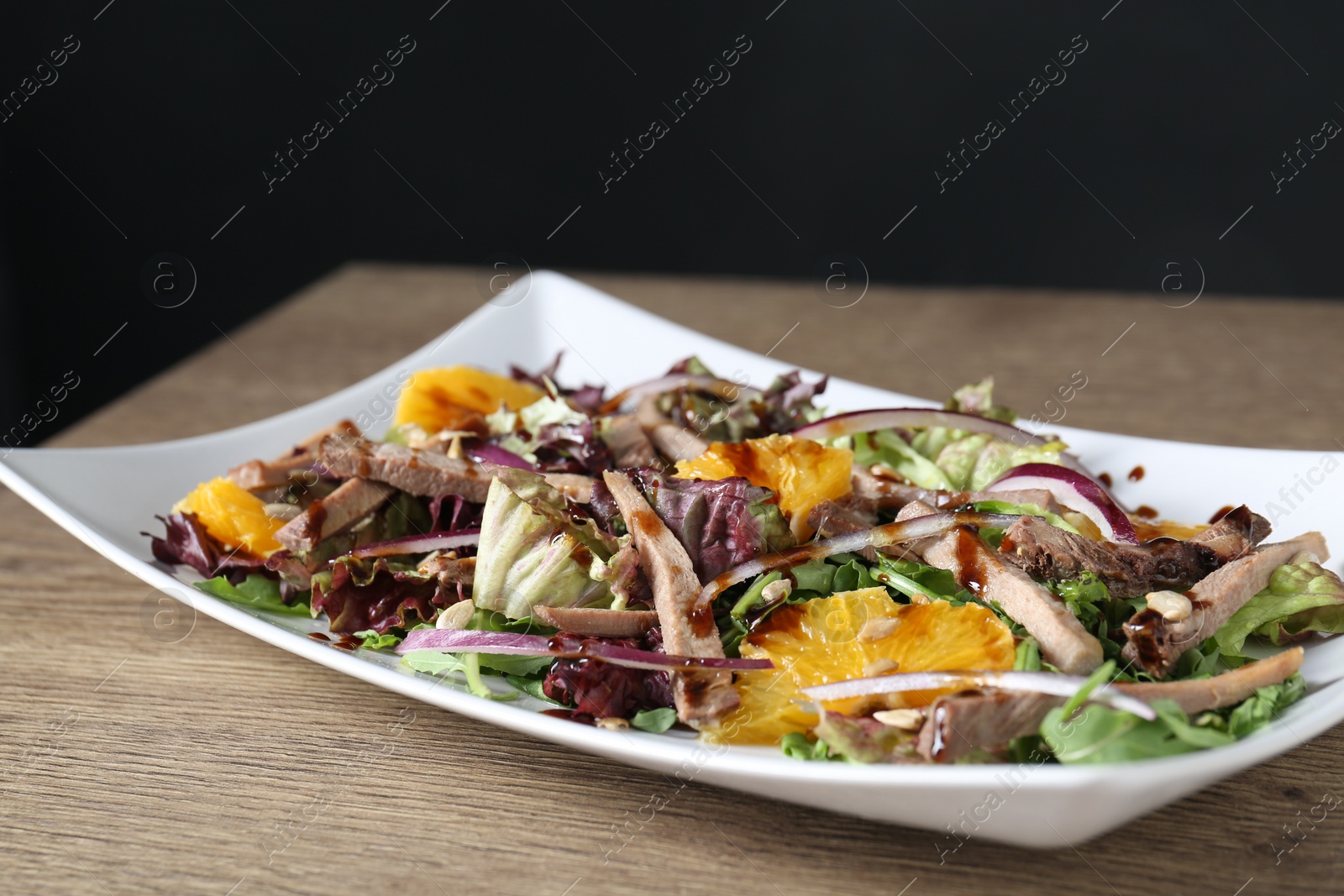 Photo of Delicious salad with beef tongue, orange and onion on wooden table, closeup