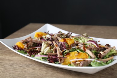 Delicious salad with beef tongue, orange and onion on wooden table, closeup