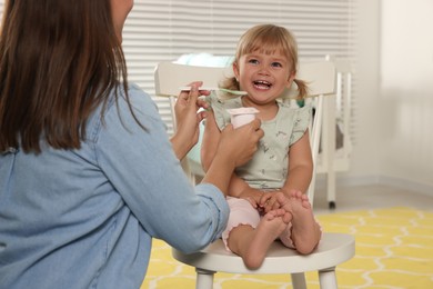 Photo of Mother feeding her cute little child with yogurt at home