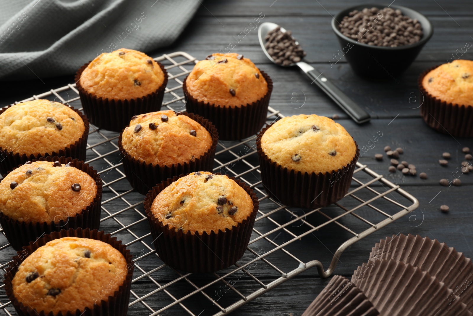 Photo of Delicious freshly baked muffins with chocolate chips on dark gray table