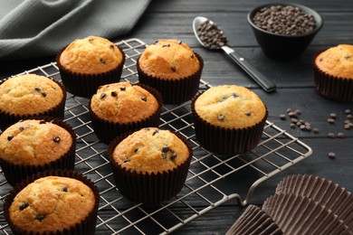 Photo of Delicious freshly baked muffins with chocolate chips on dark gray table