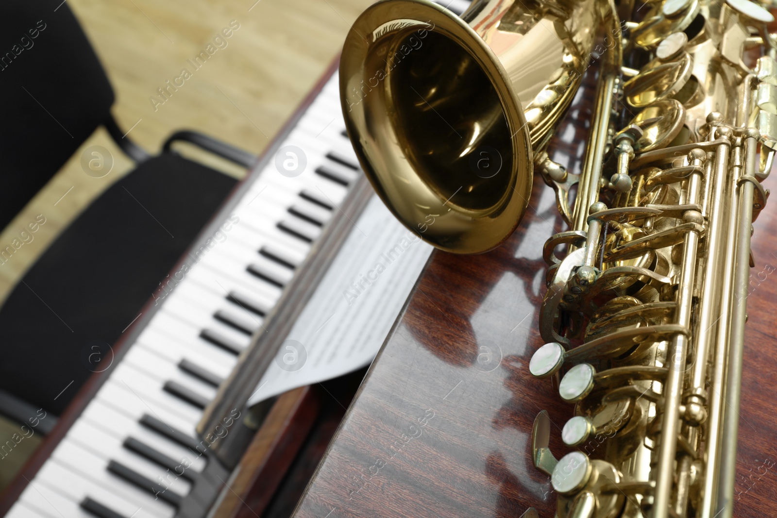 Photo of Beautiful saxophone on piano, closeup. Space for text