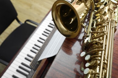 Photo of Beautiful saxophone on piano, closeup. Space for text