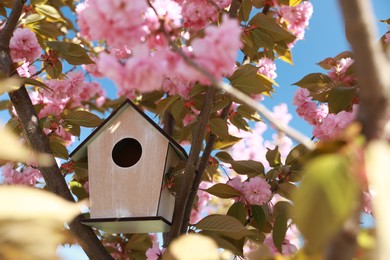 Photo of Wooden bird house on tree branches outdoors