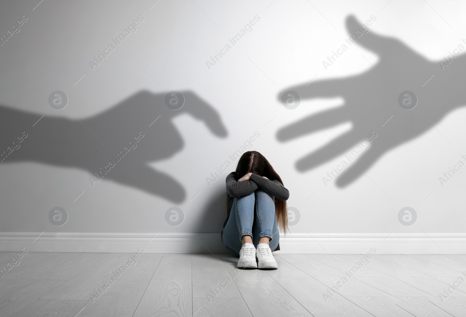 Image of Scared teenage girl suffering from sciophobia and phantoms behind her. Irrational fear of shadows