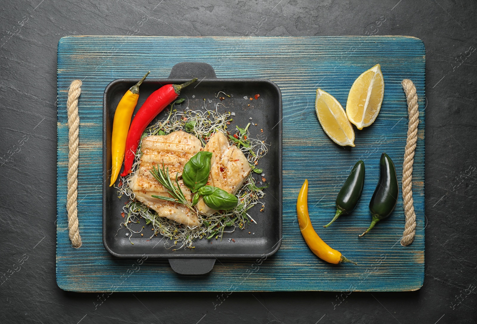 Photo of Flat lay composition with grilled fish on black table