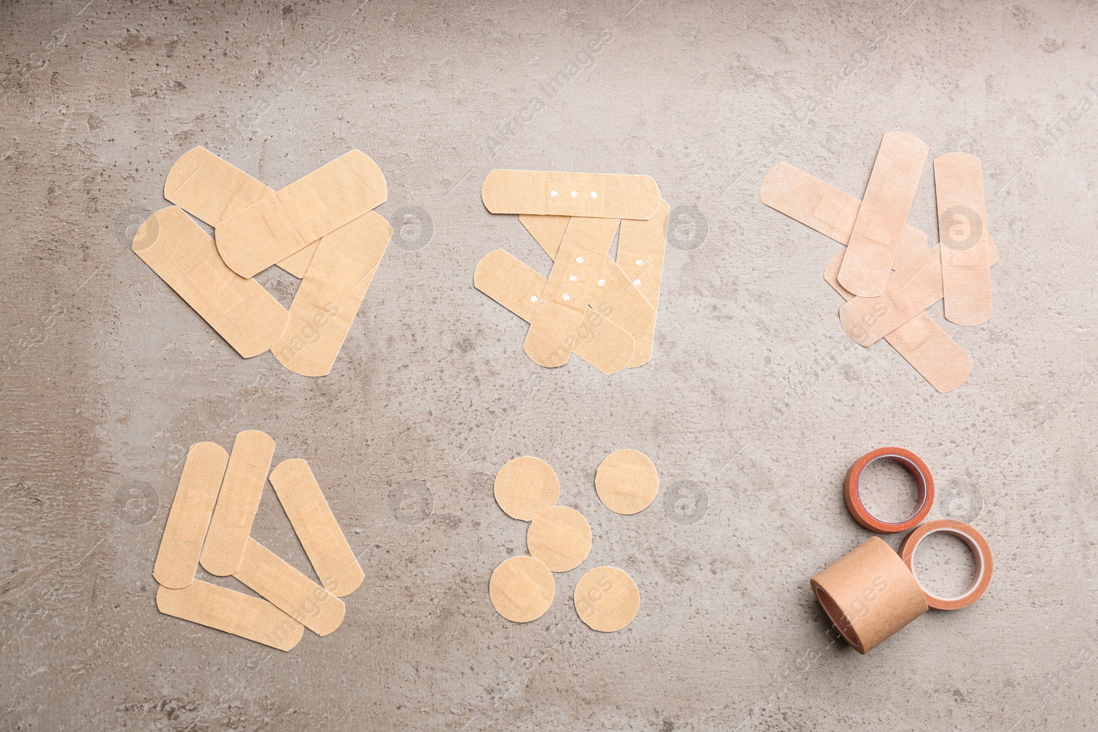 Photo of Different types of sticking plasters on stone background, flat lay