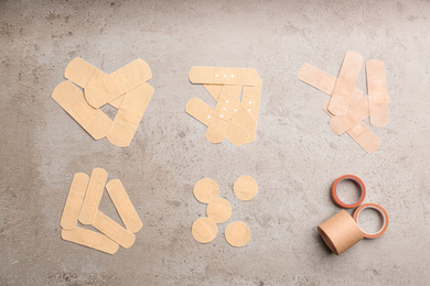 Different types of sticking plasters on stone background, flat lay