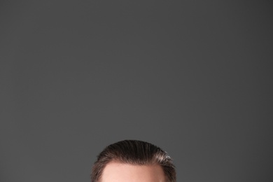 Photo of Young man with beautiful hair on grey background, closeup