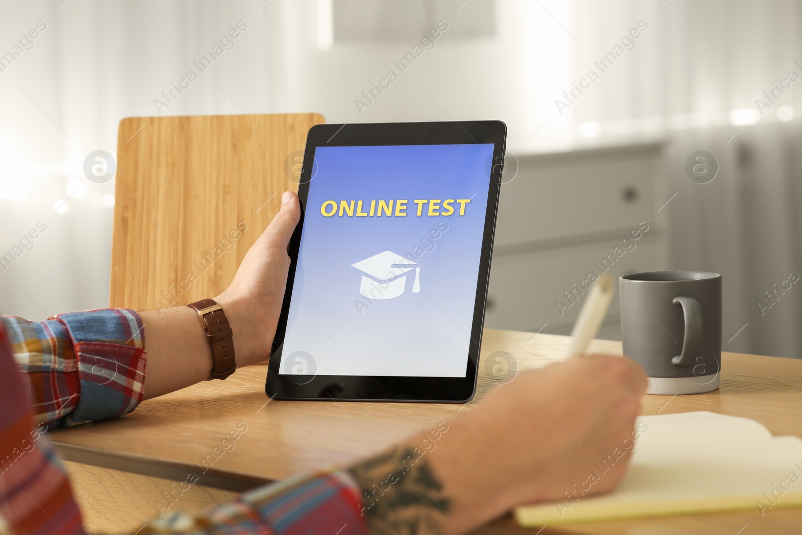 Photo of Man taking online test on tablet at desk indoors, closeup