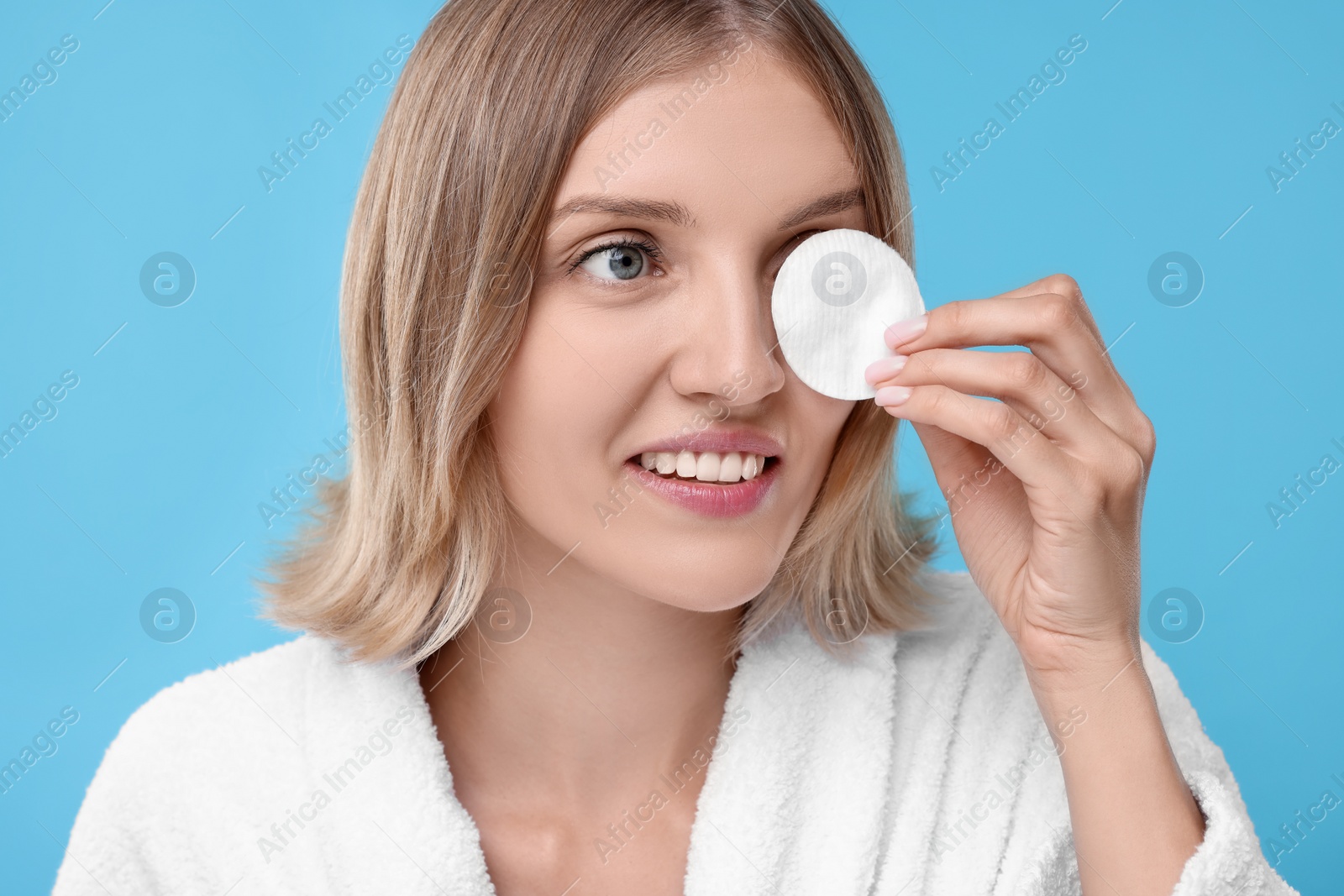 Photo of Young woman with cotton pad on light blue background