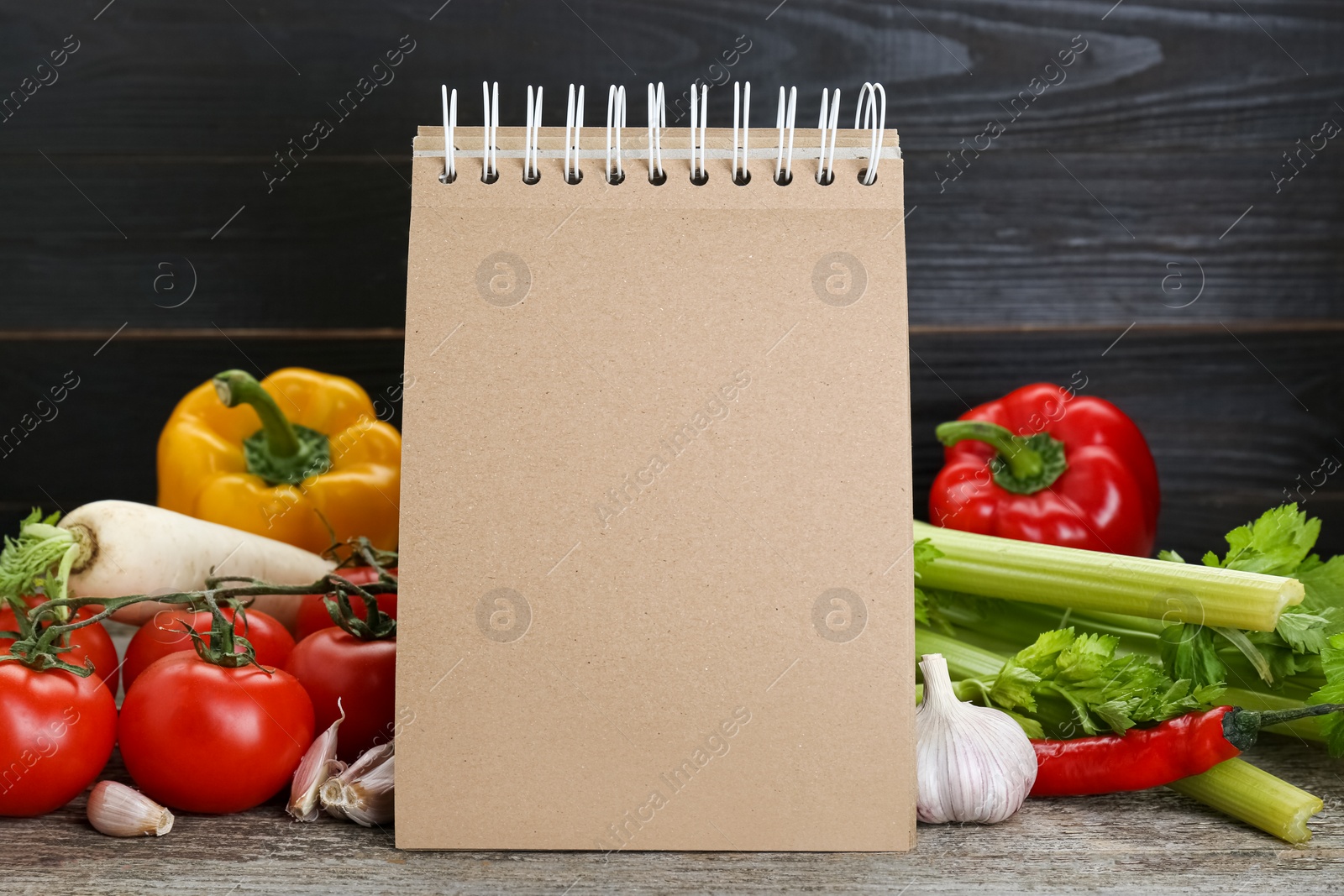 Photo of Blank recipe book and different ingredients on wooden table