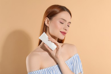 Photo of Beautiful young woman holding sun protection cream on beige background