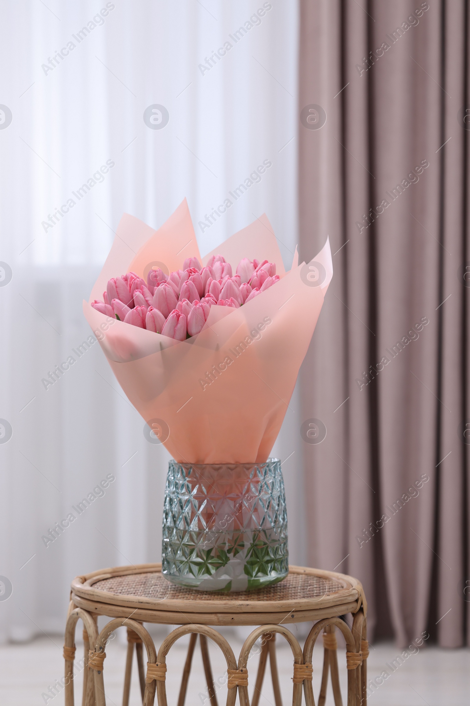 Photo of Bouquet of beautiful pink tulips in vase on table indoors